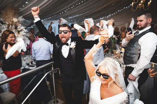 Bride, groom and guests waving napkins on the dance floor at Rossharbour Resort in Lough Erne