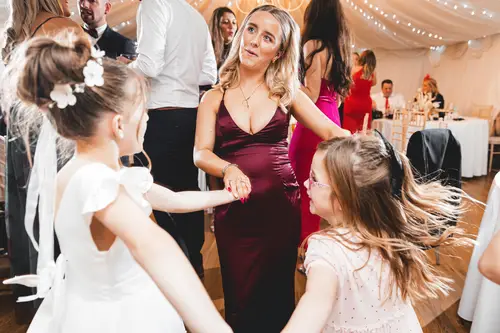 Flower girls and guests dancing under warm string lights at a Rossharbour Resort wedding reception in County Fermanagh