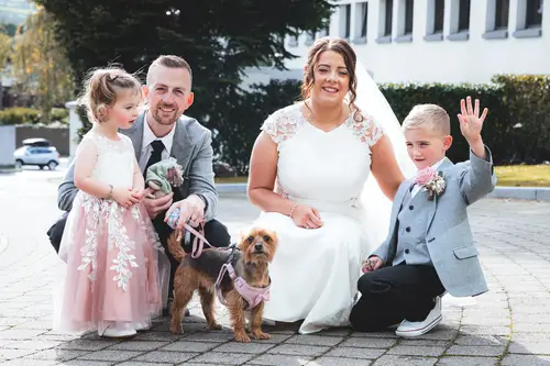 Bride with children and a dog in a joyful outdoor family portrait at Stormont, Belfast, in soft natural light