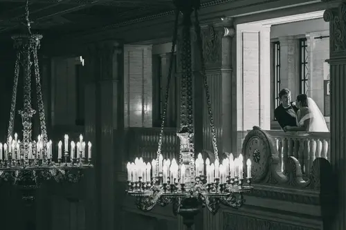 Black and white couple portrait of a bride and groom beneath a chandelier on the balcony at Stormont, Belfast