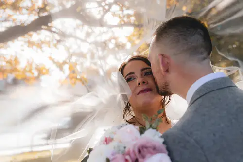 Backlit bride and groom beneath a veil for golden hour portraits at Stormont in Belfast