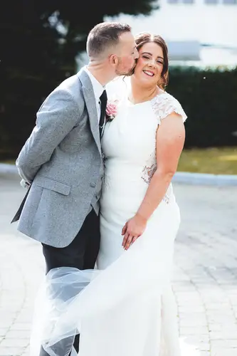 Bride kissing groom on the cheek during outdoor couple portraits at Stormont in Belfast