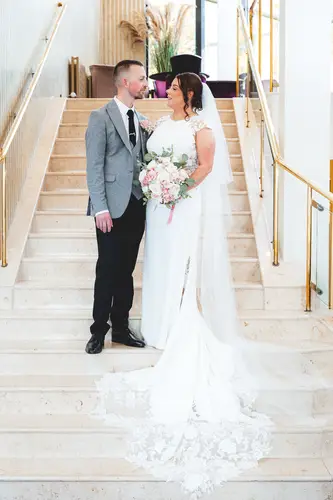Bride and groom on the staircase at Stormont in Belfast, with soft indoor light and a relaxed wedding portrait feel