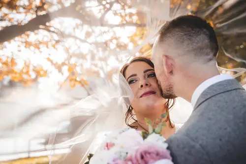 Bride and groom share a quiet veil portrait in soft golden hour light at Stormont, Belfast.