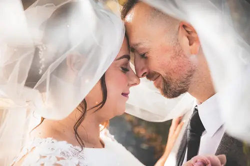 Close-up veil portrait of a bride and groom at Stormont in Belfast, sharing a quiet moment in soft light.