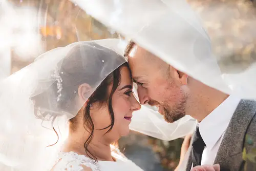 Close-up veil portrait of a bride and groom at Stormont, Belfast, in soft golden light