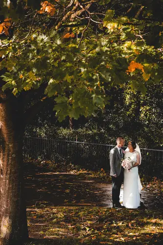 Bride and groom portrait under autumn trees at Stormont in Belfast with soft dappled light
