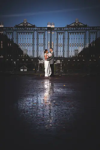 Bride and groom in a rainy night portrait at Stormont, Belfast, backlit on wet pavement with soft reflections