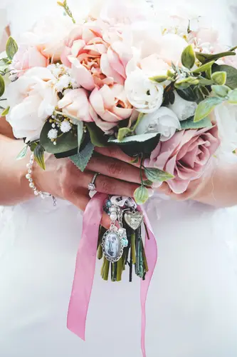 Bridal bouquet with pink roses and a bouquet charm in soft light at Stormont, Belfast