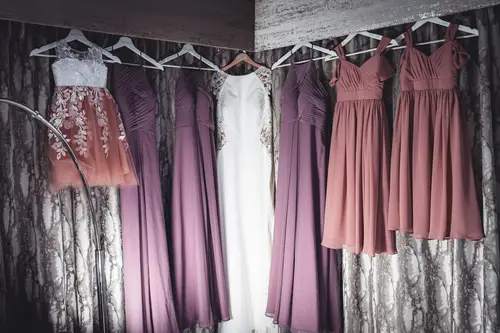 Wedding dress and bridesmaid dresses hanging in soft light at Stormont in Belfast