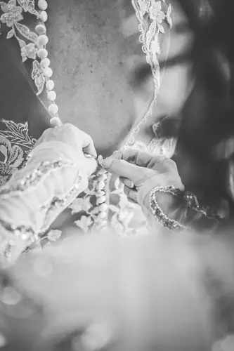 Black and white detail of lace wedding dress buttons during bridal prep at Stormont in Belfast.
