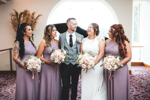 Bridal party portrait at Stormont in Belfast with lilac bridesmaid dresses, bouquets and soft window light