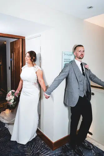 Bride and groom holding hands during a quiet first look in a natural light corridor at Stormont, Belfast