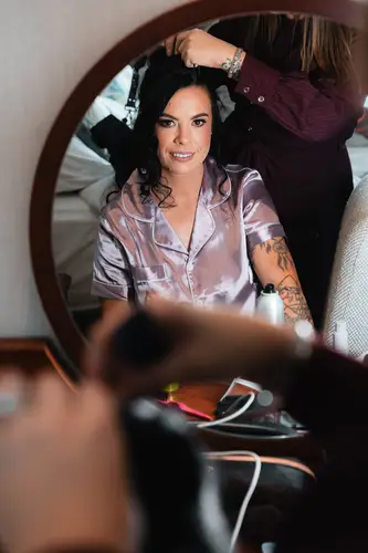 Bride in a silk robe having her hair styled in soft morning light at Stormont in Belfast