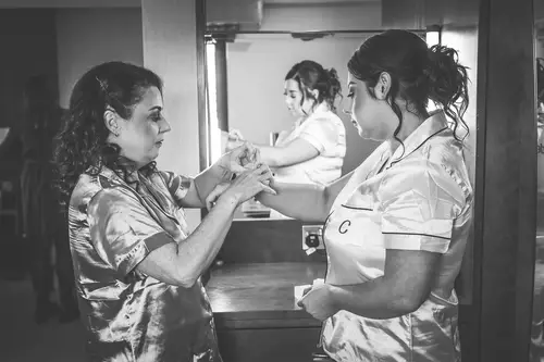Black and white bridal prep at Stormont in Belfast, with a bridesmaid helping the bride in her robe during a quiet mirror moment