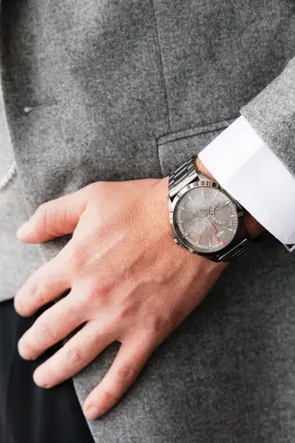 Close-up of a wristwatch and suit during groom prep at Stormont in Belfast, lit by soft natural light.