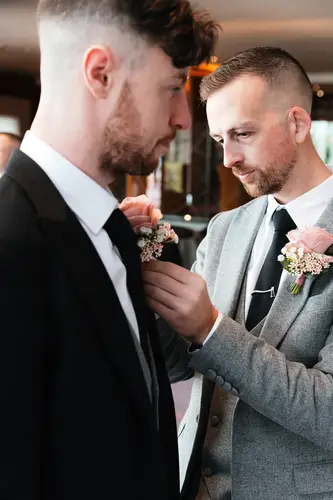 Groomsman fixing a buttonhole during relaxed wedding prep at Stormont in Belfast