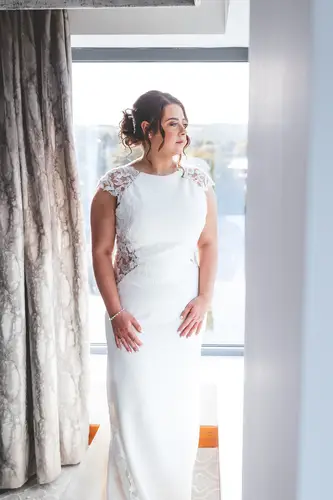 Bride in her wedding dress by soft window light during morning prep at Stormont in Belfast