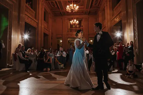 First dance at Stormont in Belfast, with the couple backlit beneath chandeliers as guests watch from the grand hall.