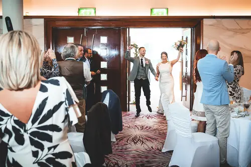 Newlyweds enter their Stormont wedding reception in Belfast as guests cheer in bright indoor light