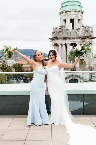 Bride and bridesmaids with bouquets on Ten Square rooftop terrace in Belfast, with a soft city backdrop
