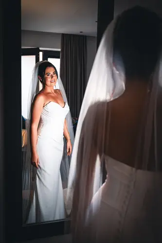 Bride in her wedding dress and veil reflected in a mirror while getting ready at Ten Square, Belfast