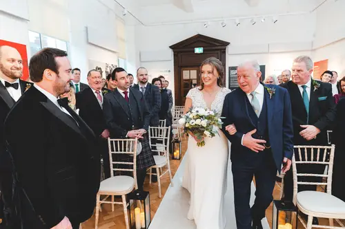 Bride walking down the aisle with her father during an emotional ceremony at Ulster Museum in Belfast