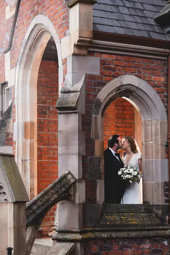 Bride and groom sharing a kiss in an arched doorway at Ulster Museum in Belfast, with brick architecture and soft natural light.