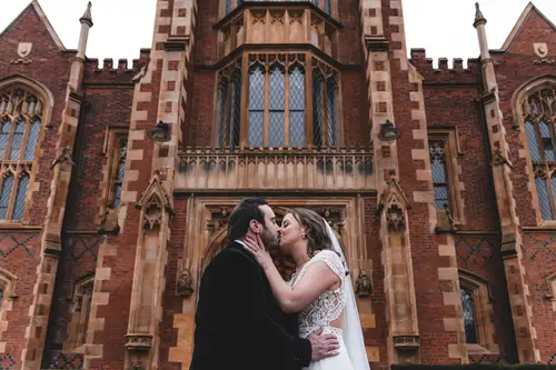 Bride and groom share a kiss outside the Ulster Museum in Belfast, framed by historic brick architecture and soft natural light