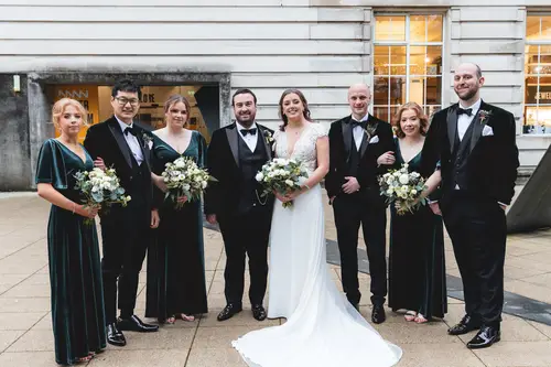 Bridal party and family portraits outside Ulster Museum in Belfast, with bouquets and formalwear in soft evening light