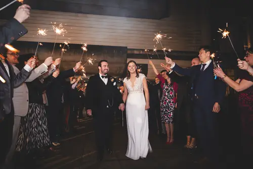 Couple surrounded by guests with sparklers during an evening reception at Ulster Museum, Belfast